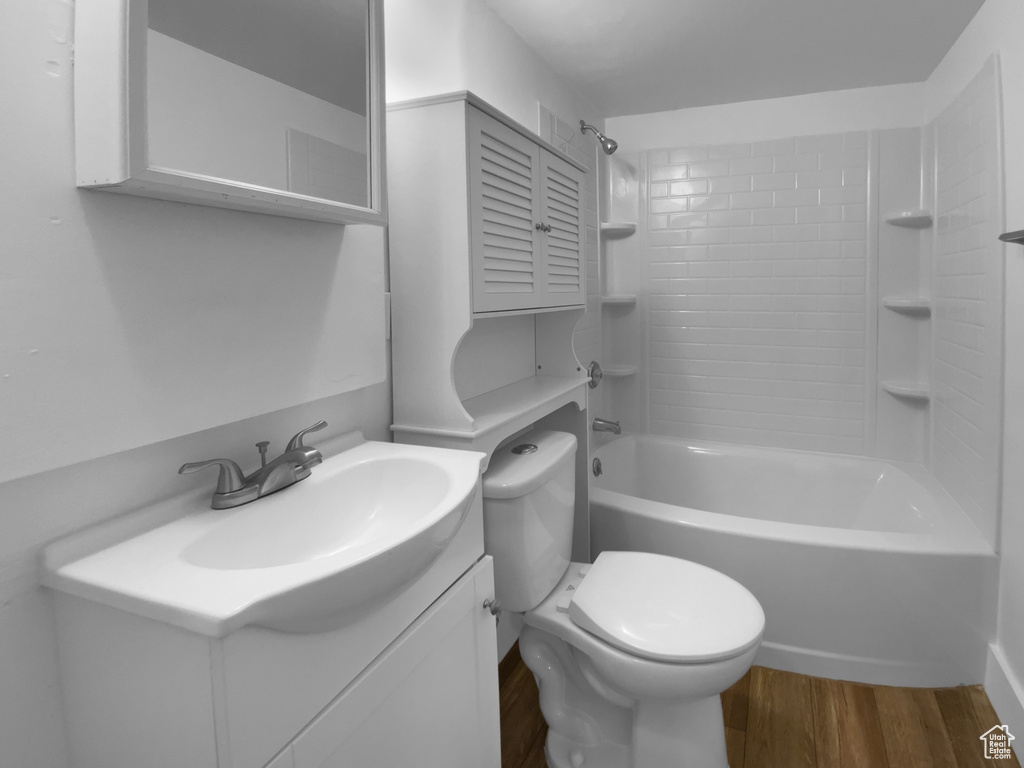 Bathroom with wood finished floors, toilet, vanity, and tub / shower combination