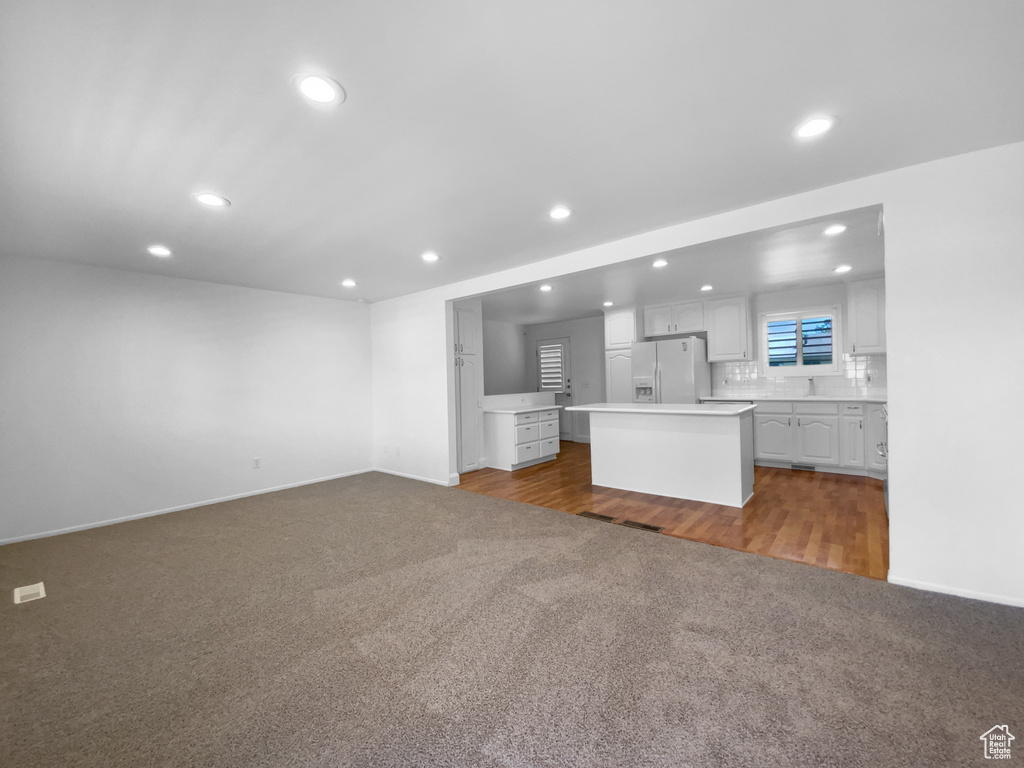 Unfurnished living room with dark carpet, recessed lighting, and baseboards