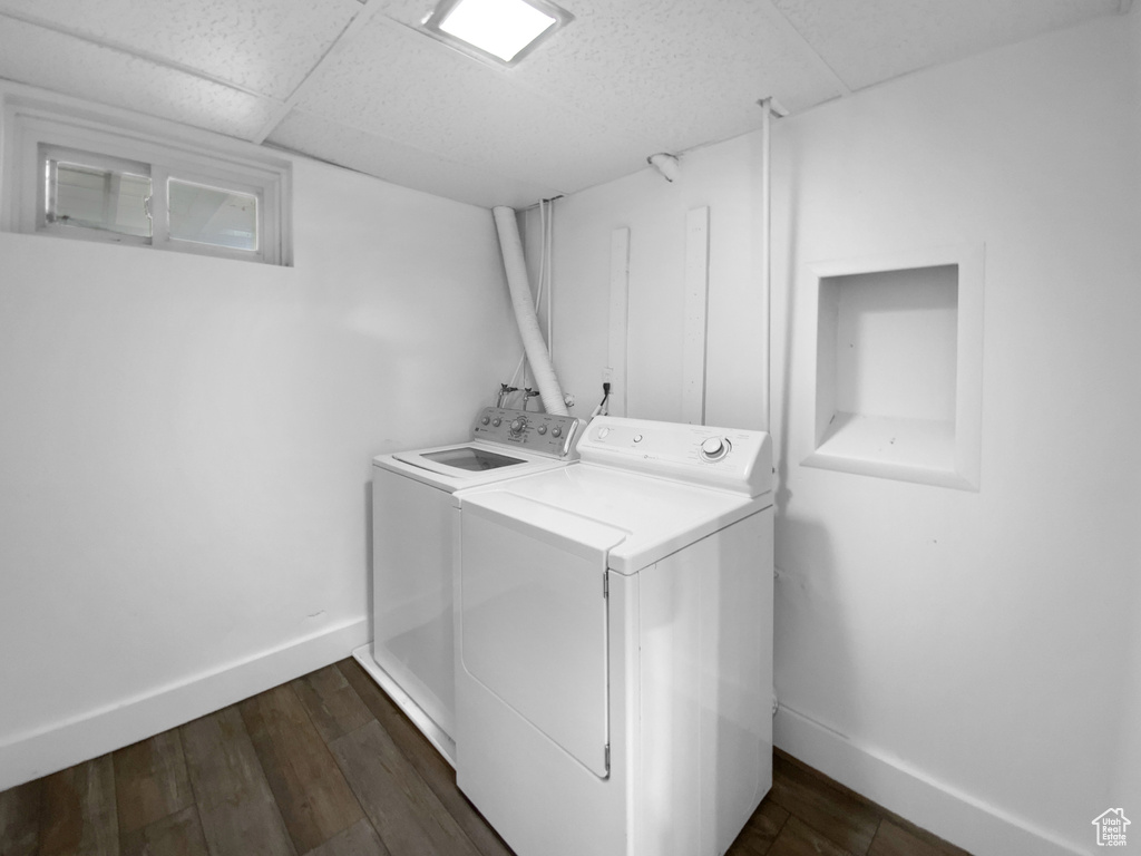 Washroom featuring washing machine and dryer, baseboards, and dark wood-type flooring