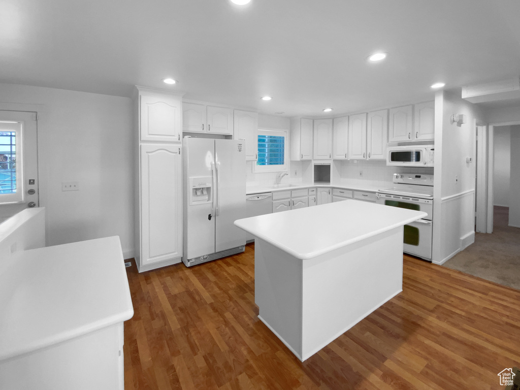 Kitchen featuring white appliances, a sink, white cabinetry, a kitchen island, and recessed lighting