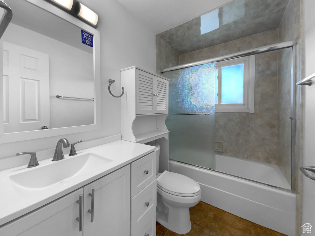Full bath featuring vanity, toilet, shower / bath combination with glass door, and tile patterned flooring
