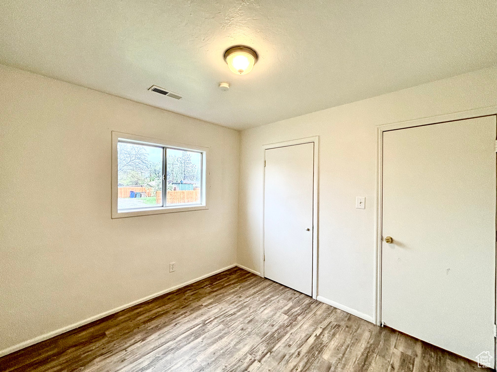 Unfurnished bedroom with wood finished floors and baseboards