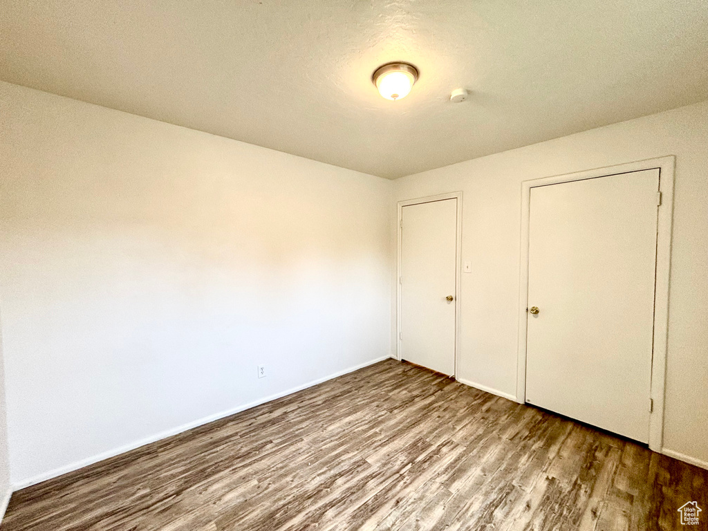 Unfurnished bedroom featuring wood finished floors and baseboards