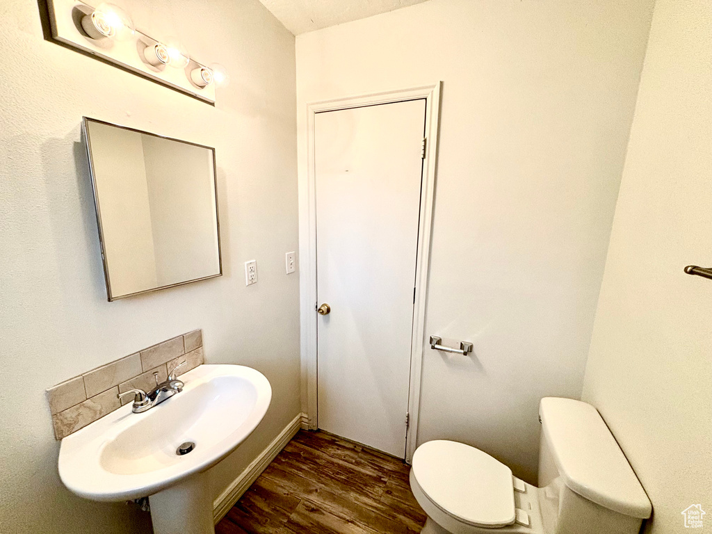 Bathroom featuring a sink, wood finished floors, and toilet