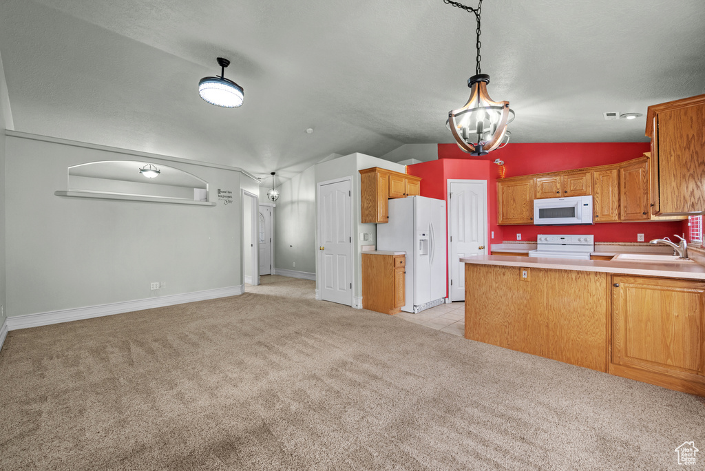 Kitchen featuring white appliances, light carpet, a sink, a peninsula, and lofted ceiling