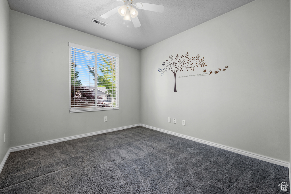 Unfurnished room with dark carpet, a textured ceiling, ceiling fan, and baseboards
