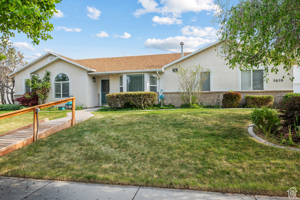 Single story home with stucco siding, a front lawn, and brick siding