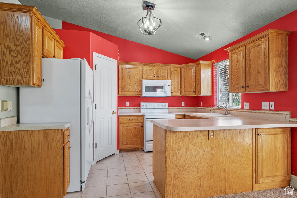 Kitchen with white appliances, a sink, a peninsula, vaulted ceiling, and light countertops