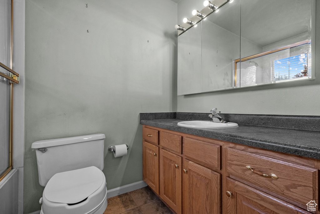 Full bathroom featuring toilet, vanity, and baseboards