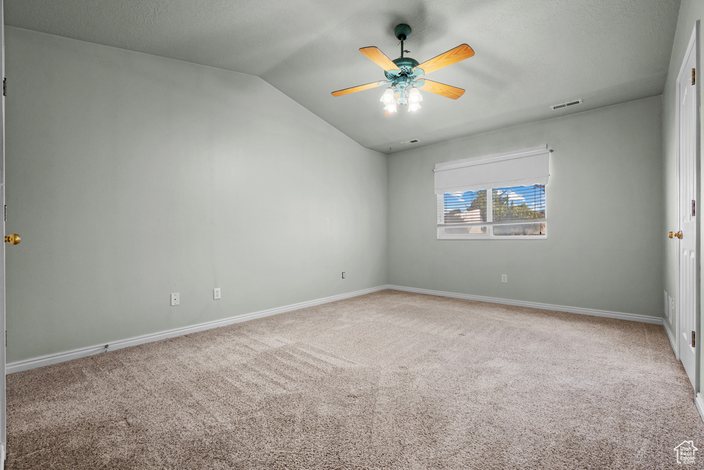 Spare room with lofted ceiling, carpet, ceiling fan, and baseboards