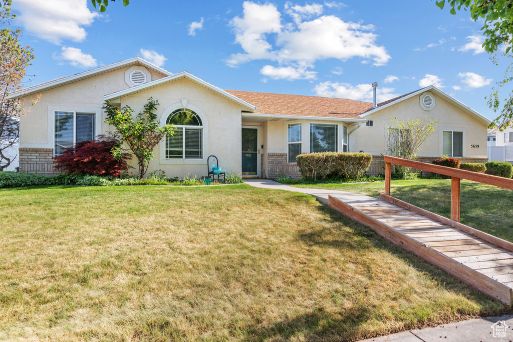 Ranch-style house featuring stucco siding and a front yard