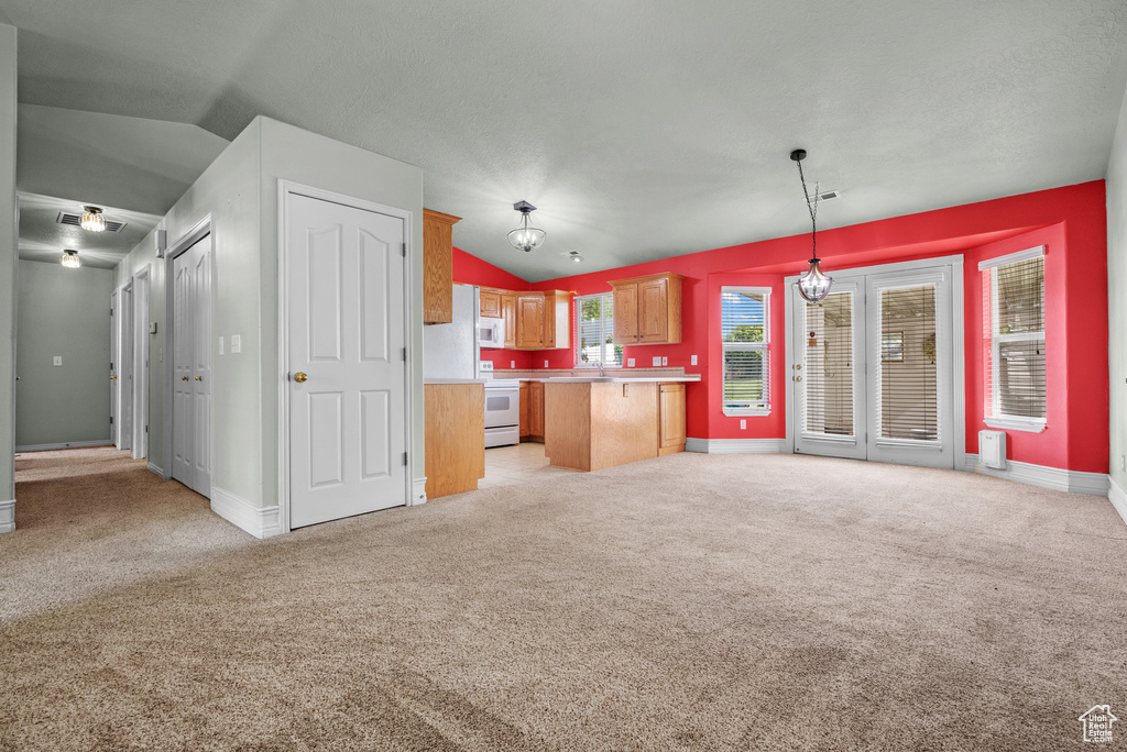 Kitchen with white appliances, lofted ceiling, open floor plan, light countertops, and light colored carpet