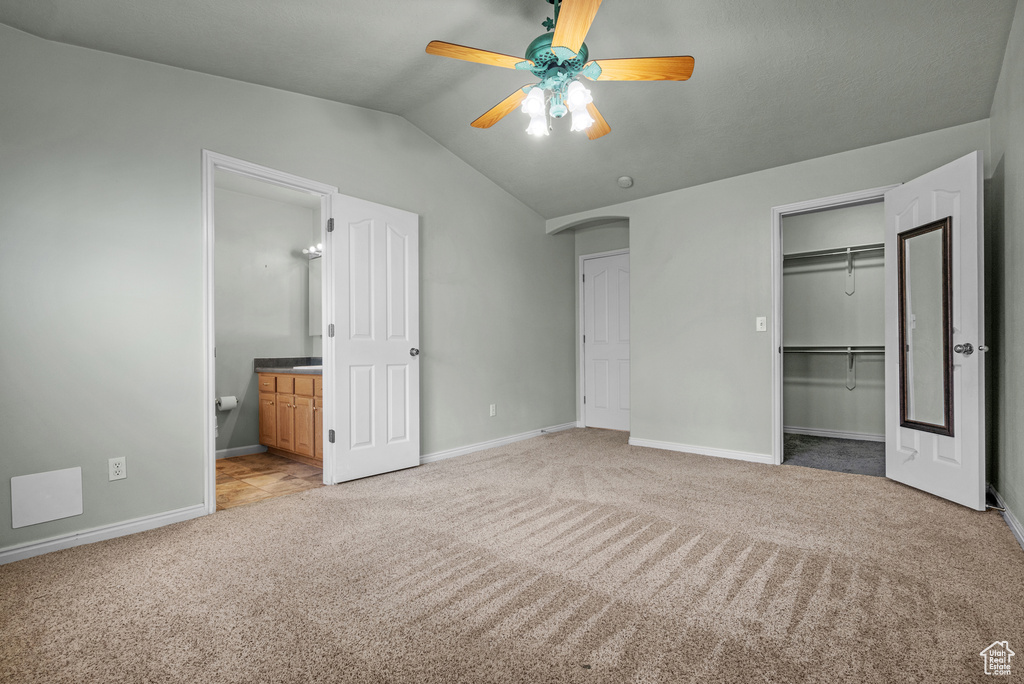 Unfurnished bedroom featuring light colored carpet, vaulted ceiling, baseboards, a closet, and connected bathroom