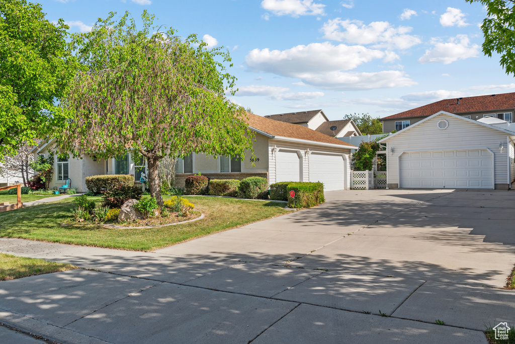 Obstructed view of property with driveway, a front yard, a garage, and an outdoor structure