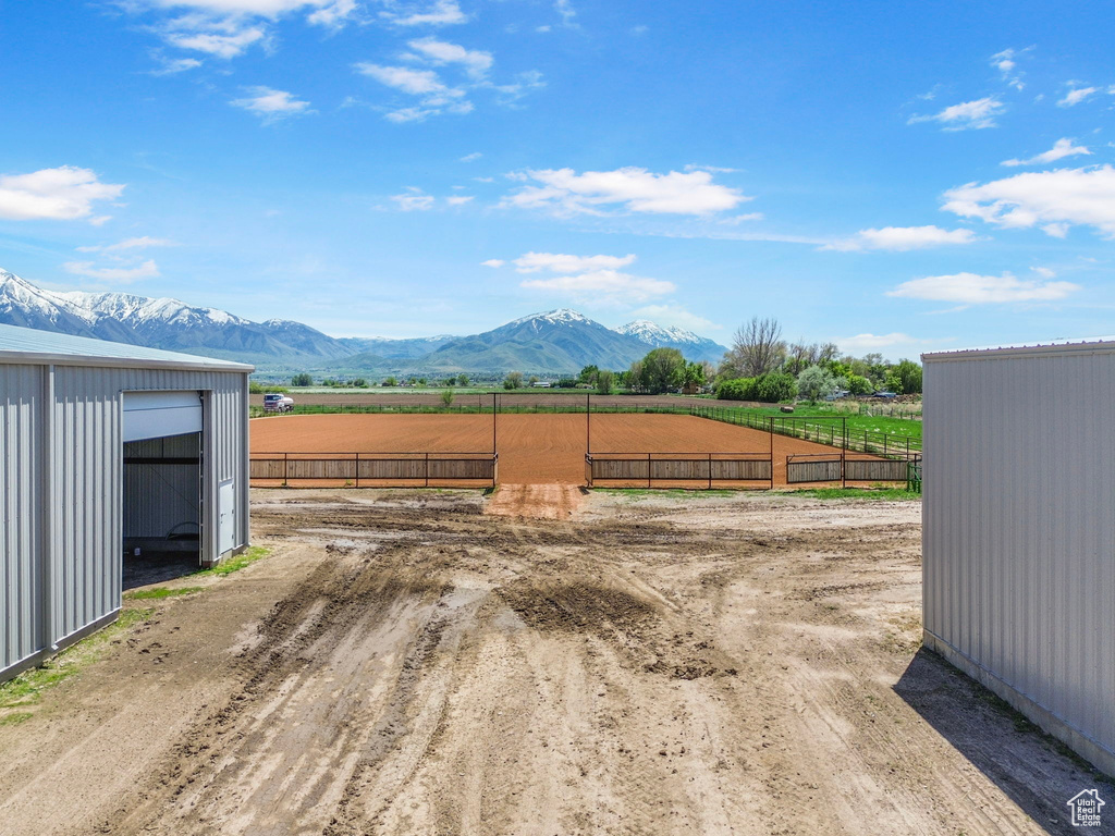 View of yard featuring an enclosed riding area, a rural view, a mountain view, and fence