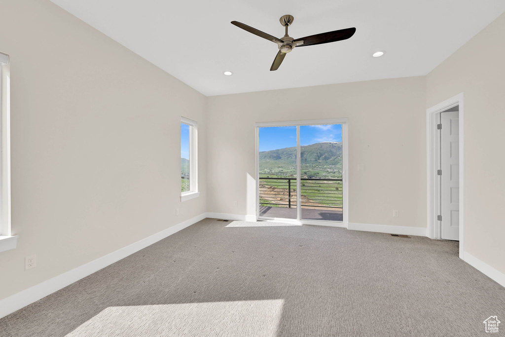 Spare room featuring carpet flooring, a ceiling fan, baseboards, a mountain view, and recessed lighting