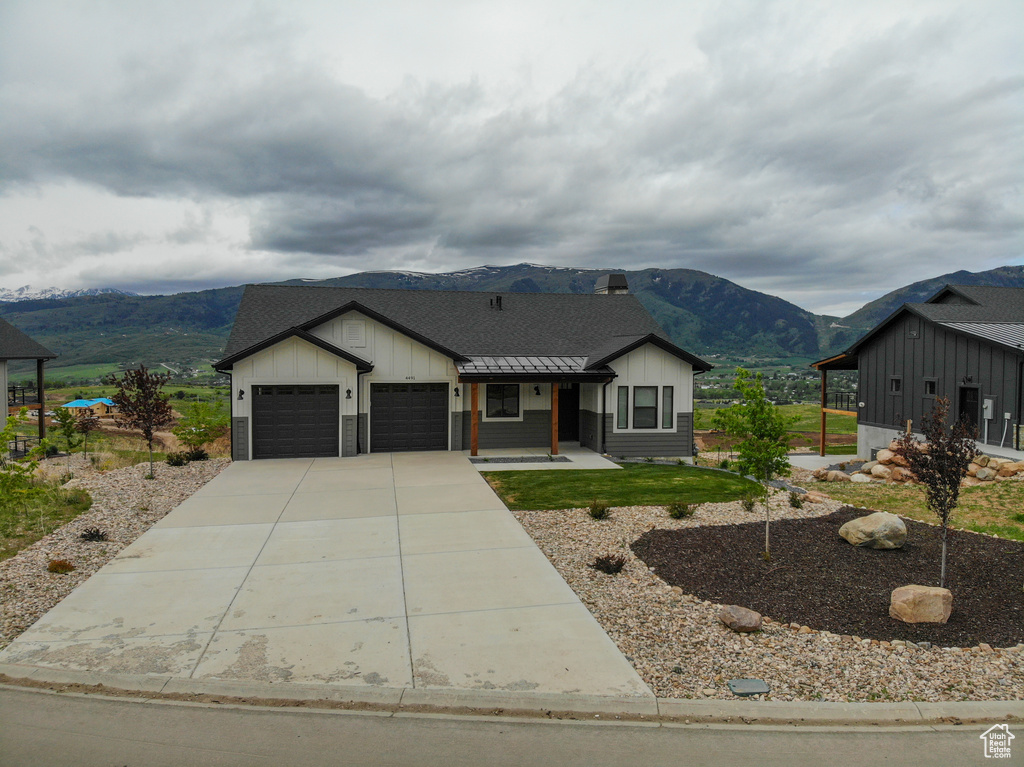 Modern farmhouse style home featuring board and batten siding, a mountain view, a garage, concrete driveway, and roof with shingles