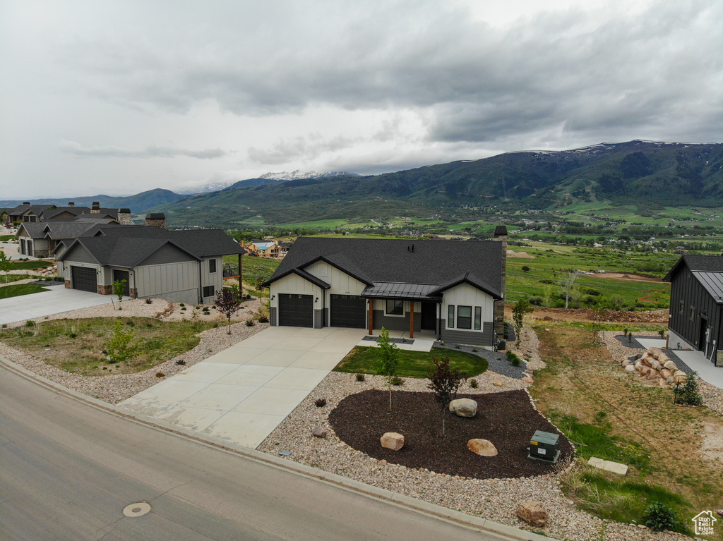 Modern farmhouse style home with a mountain view, a garage, driveway, and a shingled roof