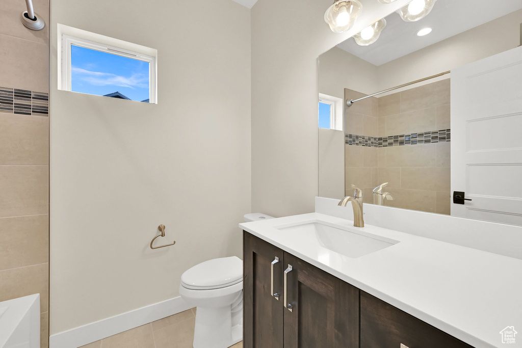 Bathroom featuring toilet, a shower, tile patterned floors, vanity, and baseboards