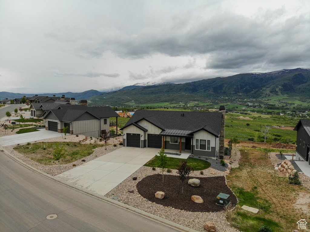 View of front of property with a mountain view, a garage, and driveway