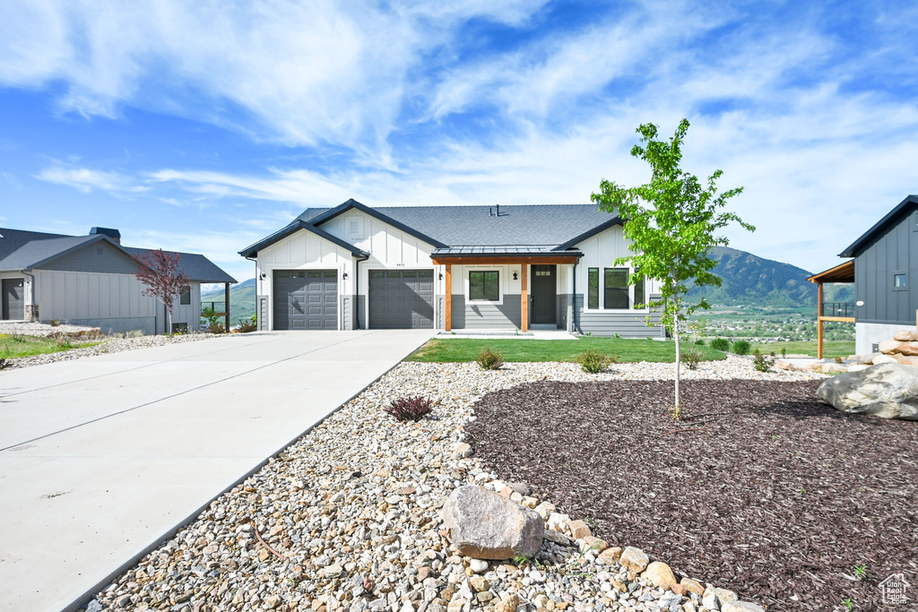 Modern farmhouse style home featuring board and batten siding, concrete driveway, an attached garage, and a mountain view