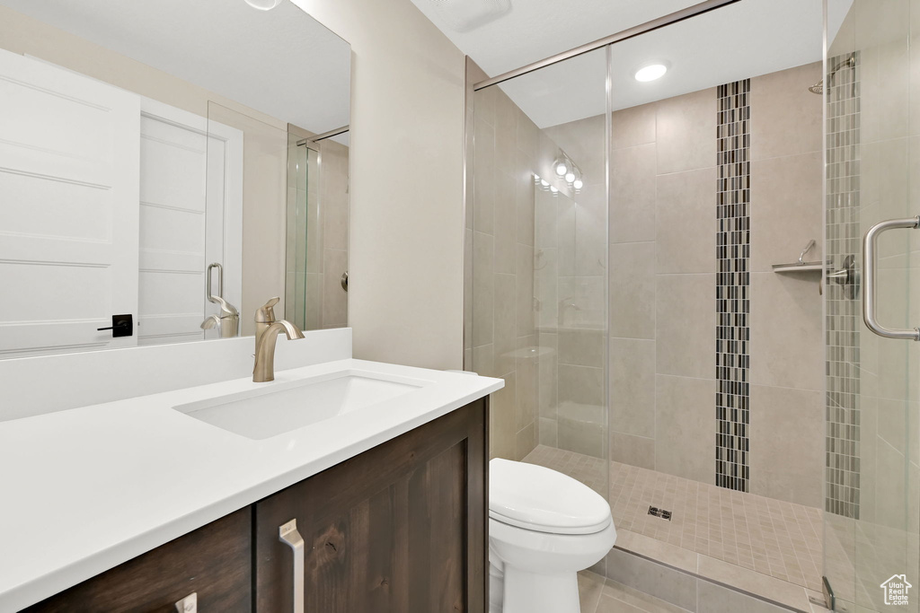 Full bathroom featuring a stall shower, toilet, vanity, and tile patterned floors