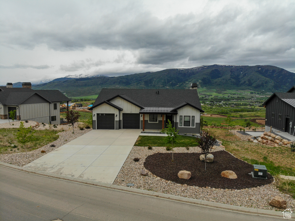 Modern inspired farmhouse featuring a mountain view, board and batten siding, an attached garage, and driveway