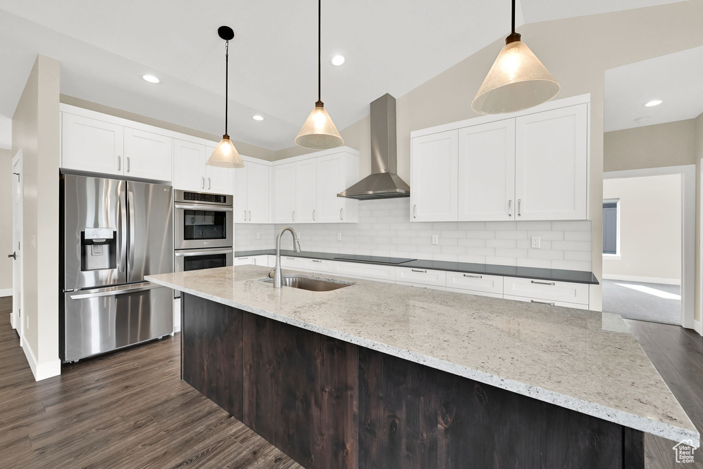 Kitchen with stainless steel appliances, a sink, wall chimney exhaust hood, backsplash, and recessed lighting