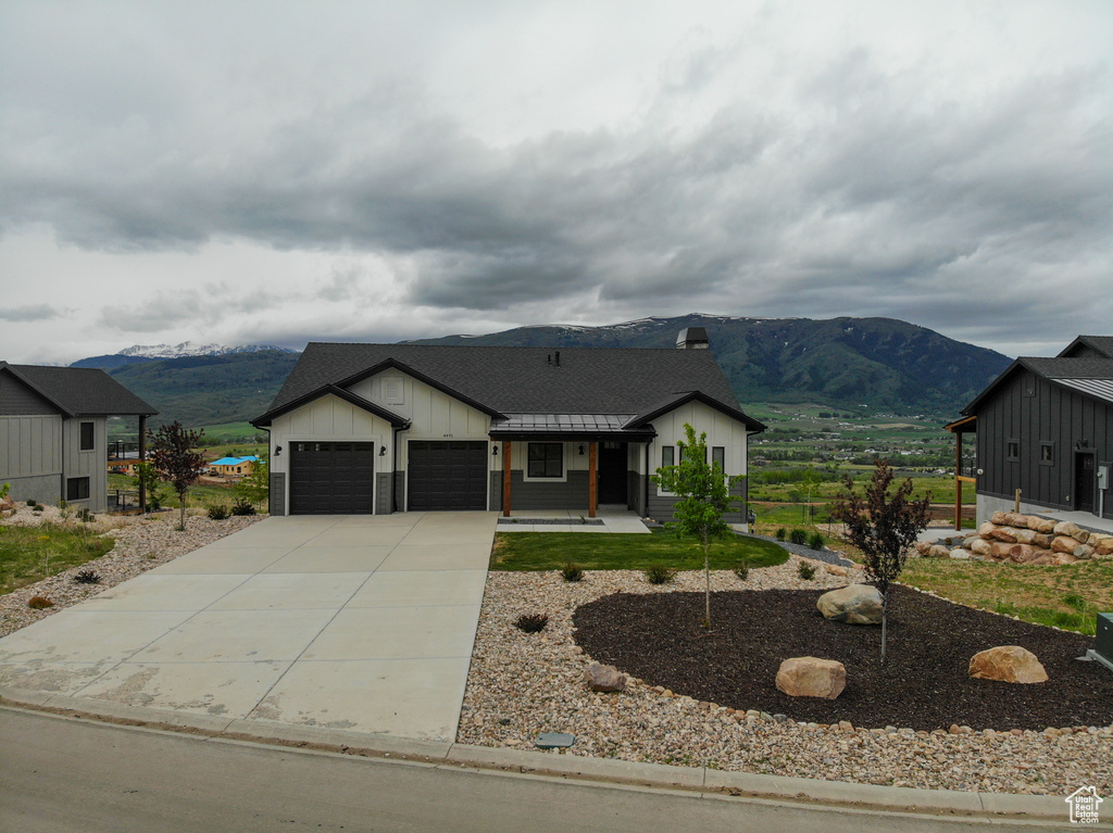Modern inspired farmhouse featuring a mountain view, an attached garage, board and batten siding, driveway, and a chimney