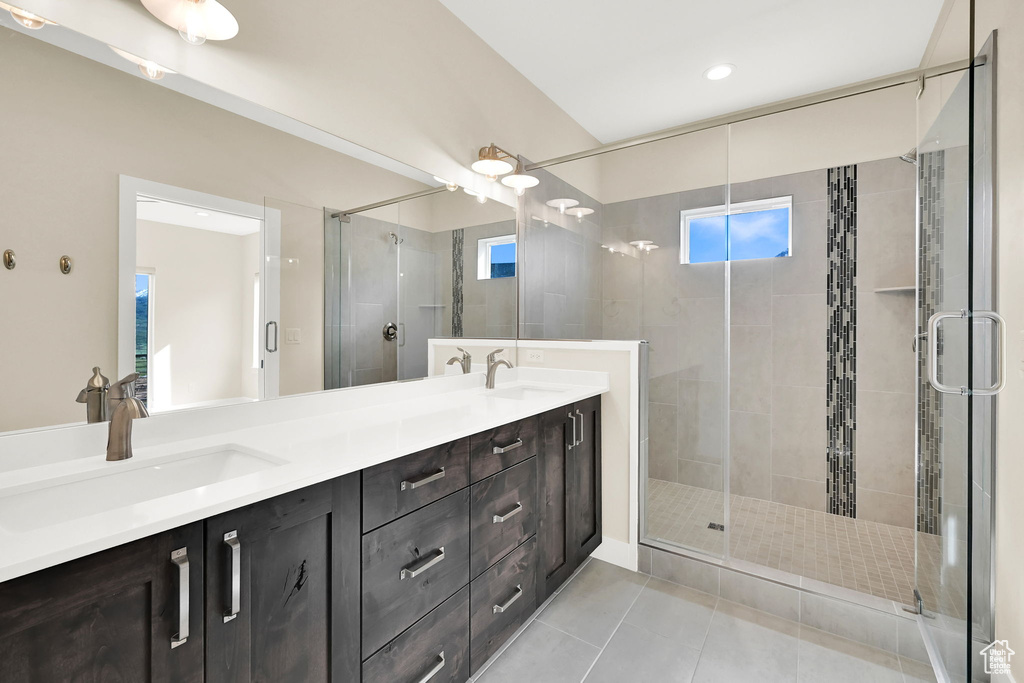Full bath with a shower stall, tile patterned flooring, and double vanity