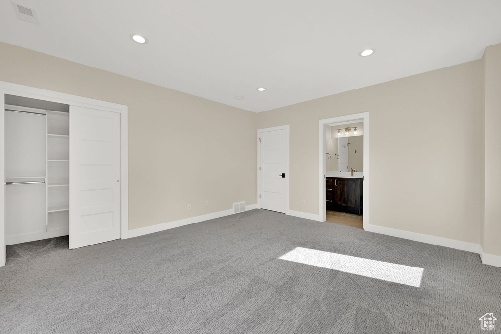 Unfurnished bedroom featuring carpet, recessed lighting, baseboards, ensuite bathroom, and a closet