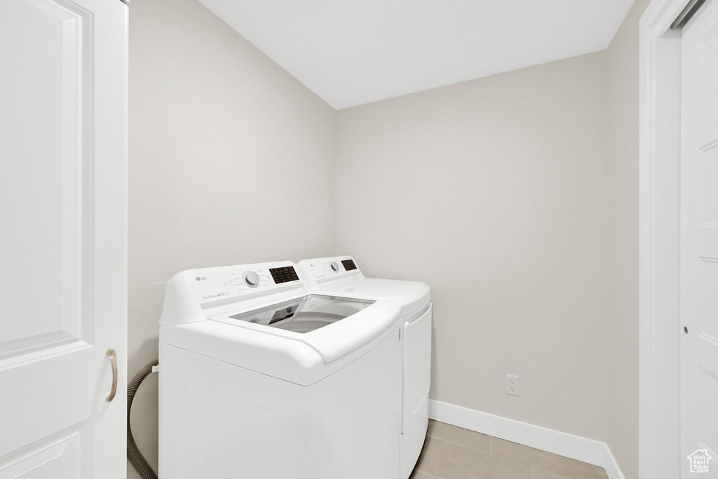 Clothes washing area featuring independent washer and dryer, baseboards, and light tile patterned floors
