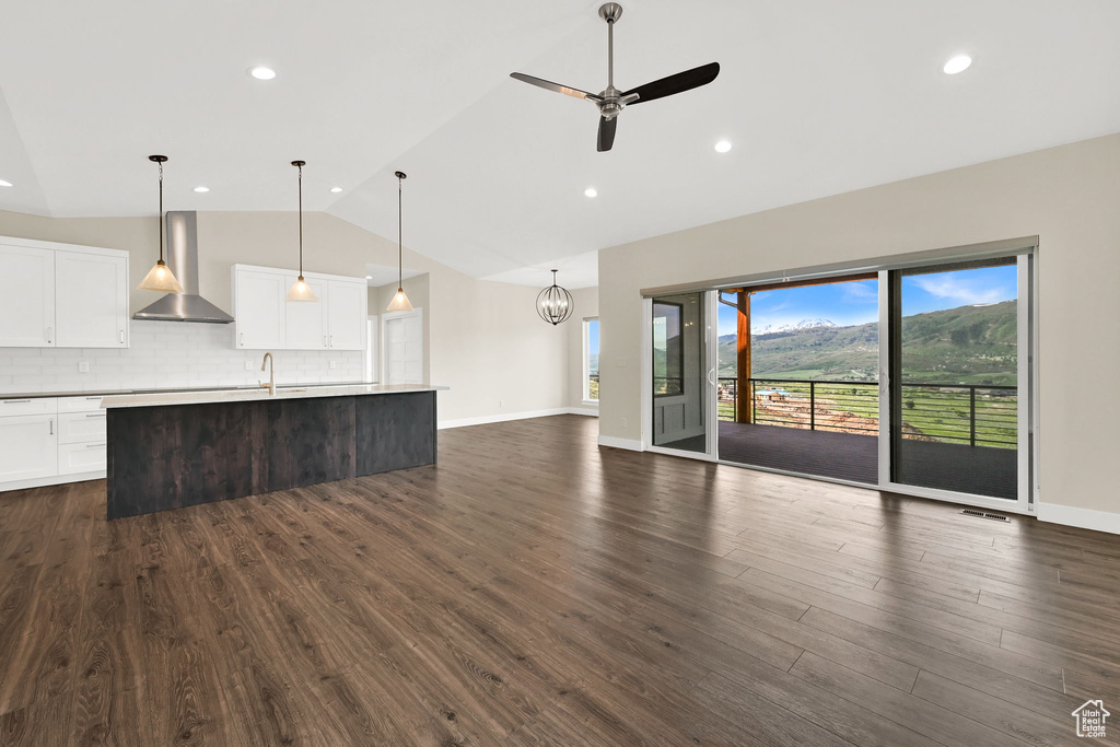 Unfurnished living room with a ceiling fan, dark wood-style floors, recessed lighting, high vaulted ceiling, and a chandelier