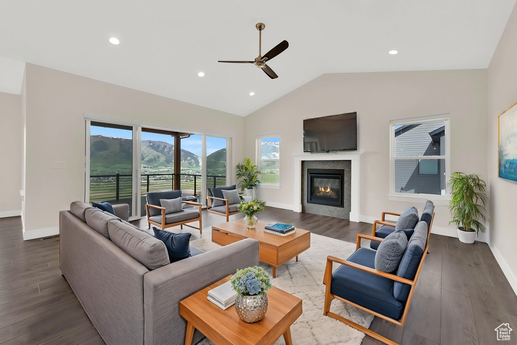 Living area featuring ceiling fan, lofted ceiling, wood finished floors, a glass covered fireplace, and recessed lighting