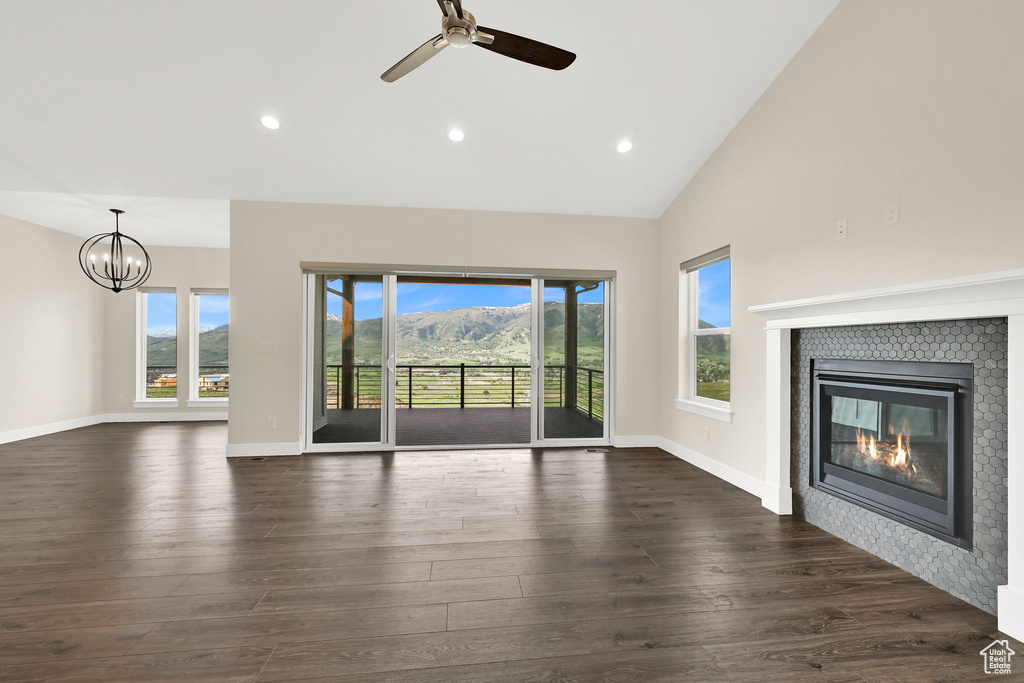 Unfurnished living room with a tile fireplace, dark wood-style floors, a ceiling fan, high vaulted ceiling, and recessed lighting