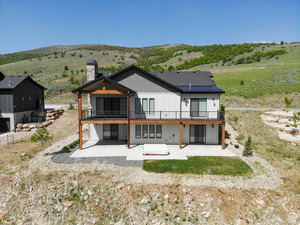 Back of house featuring a patio, a chimney, and a mountain view