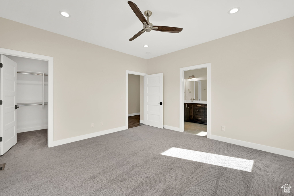 Unfurnished bedroom with carpet, a walk in closet, baseboards, recessed lighting, and a closet