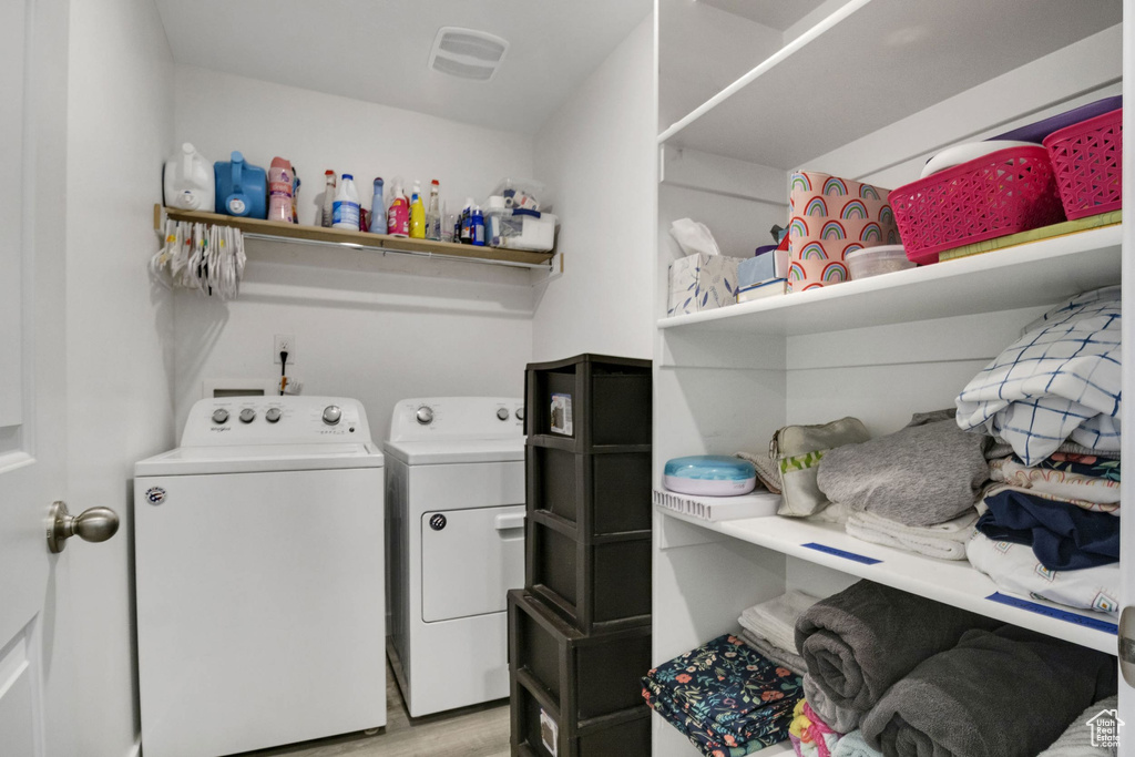 Laundry room with washing machine and dryer and light wood-style flooring