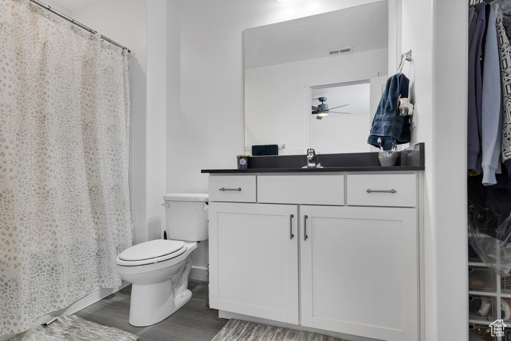 Full bathroom with wood finished floors, toilet, vanity, and ceiling fan