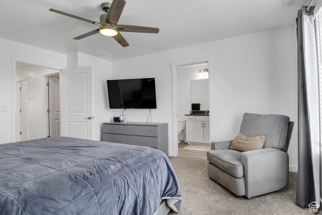 Carpeted bedroom with a ceiling fan, connected bathroom, and baseboards