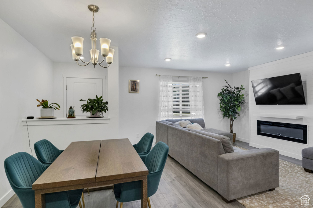 Dining area with a chandelier, wood finished floors, a glass covered fireplace, baseboards, and recessed lighting