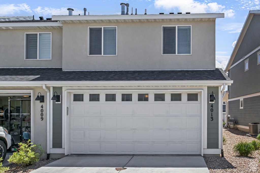 View of front facade featuring a garage, stucco siding, and concrete driveway