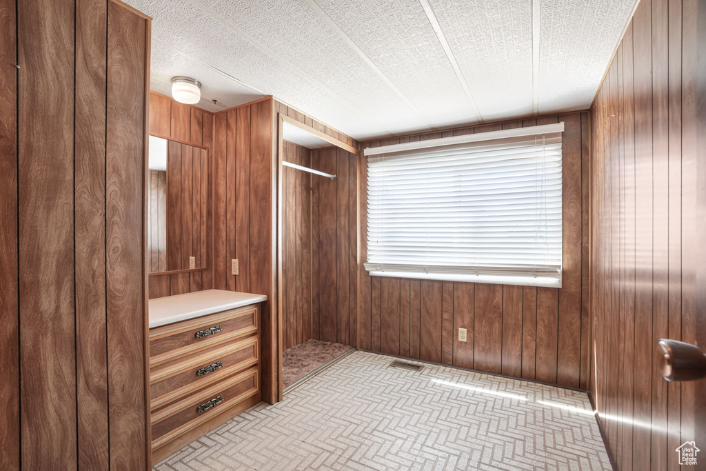 Unfurnished bedroom with wood walls and a textured ceiling