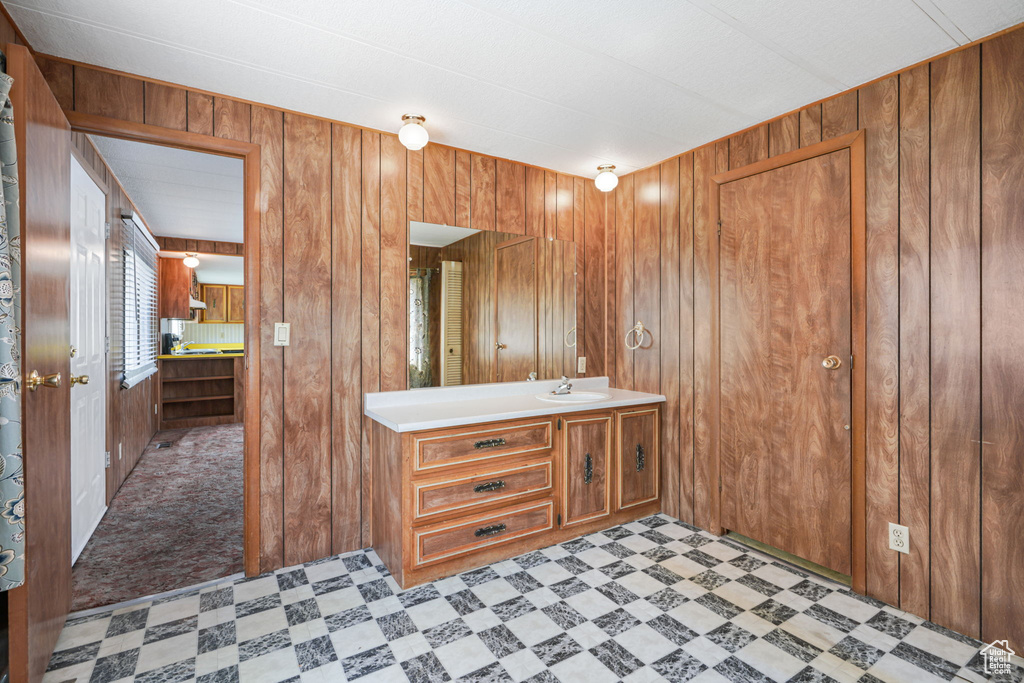 Bathroom featuring wood walls, tile patterned floors, and vanity