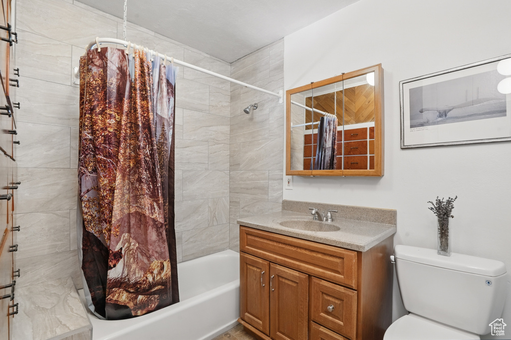 Bathroom featuring toilet, vanity, and shower / bathtub combination with curtain