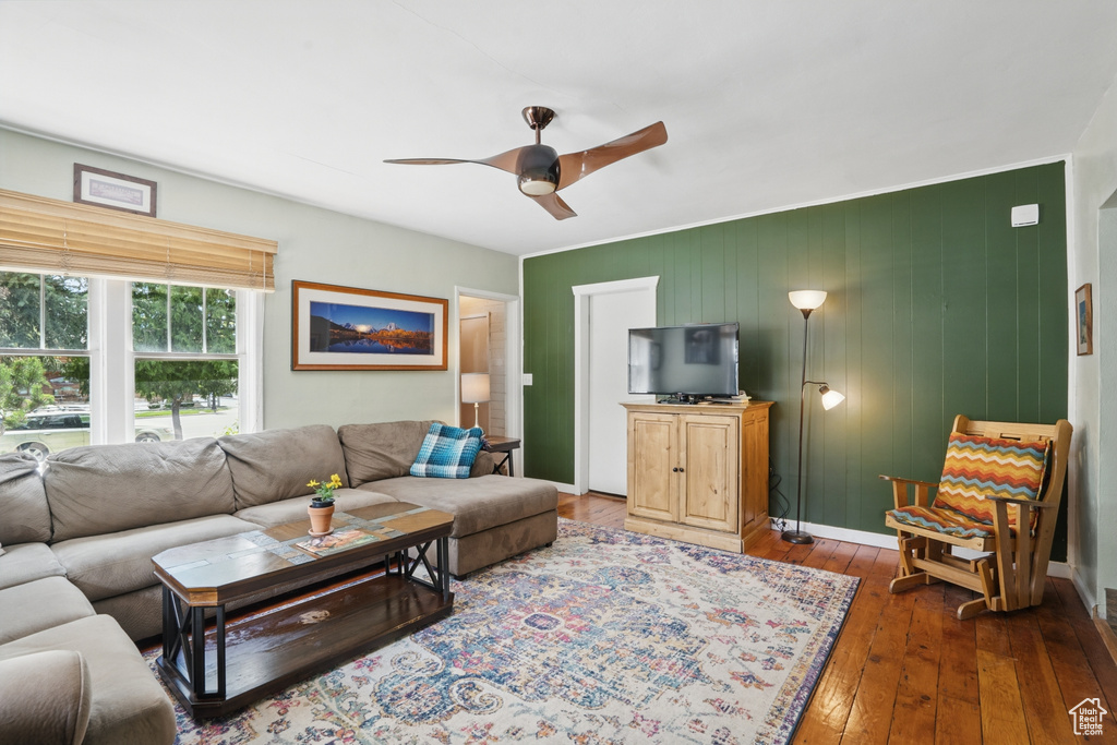 Living area with a ceiling fan, dark wood finished floors, and baseboards