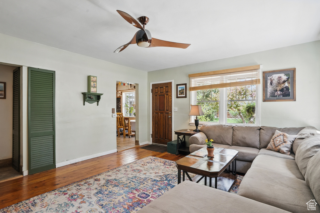 Living area with hardwood / wood-style floors, ceiling fan, and baseboards