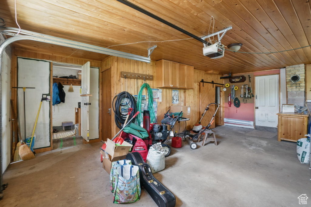 Garage with a garage door opener, wooden ceiling, and wooden walls
