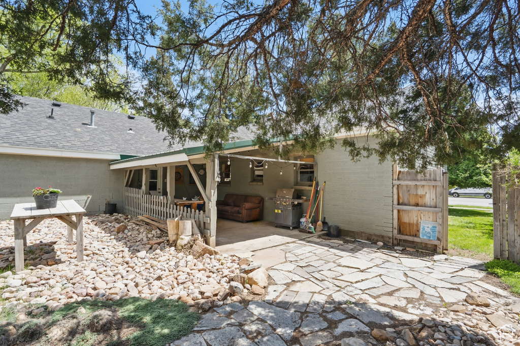 Back of house featuring concrete driveway, a patio area, a shingled roof, and concrete block siding