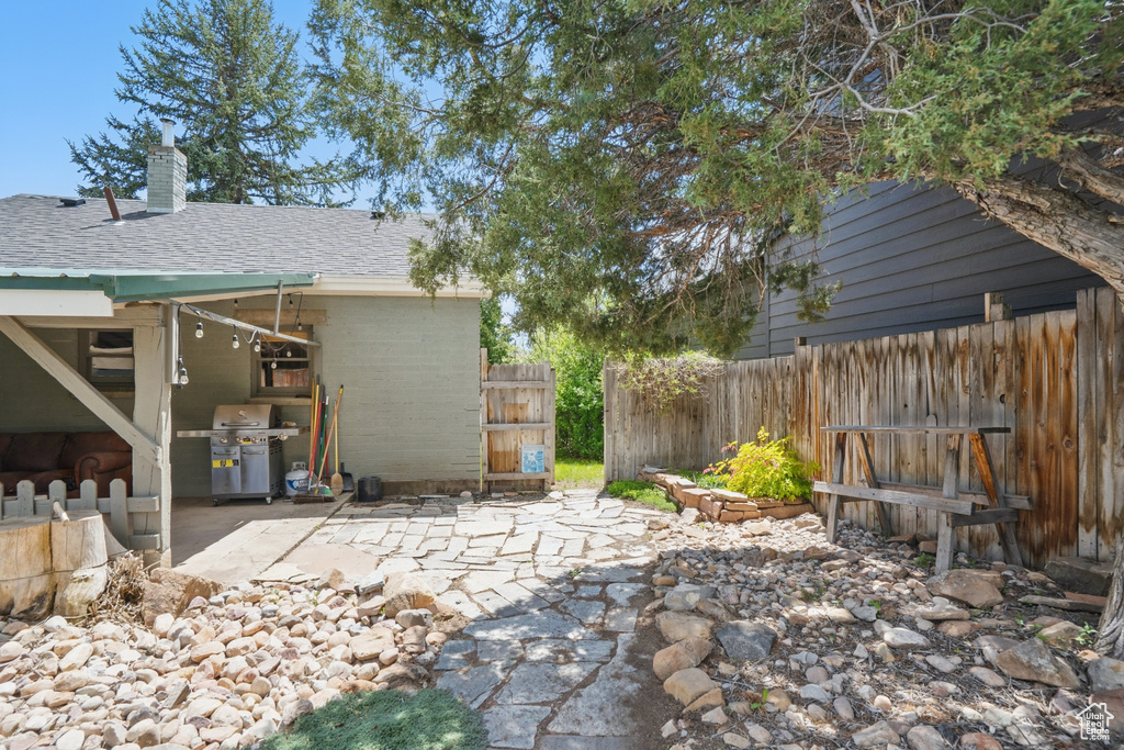 View of patio featuring fence and a grill